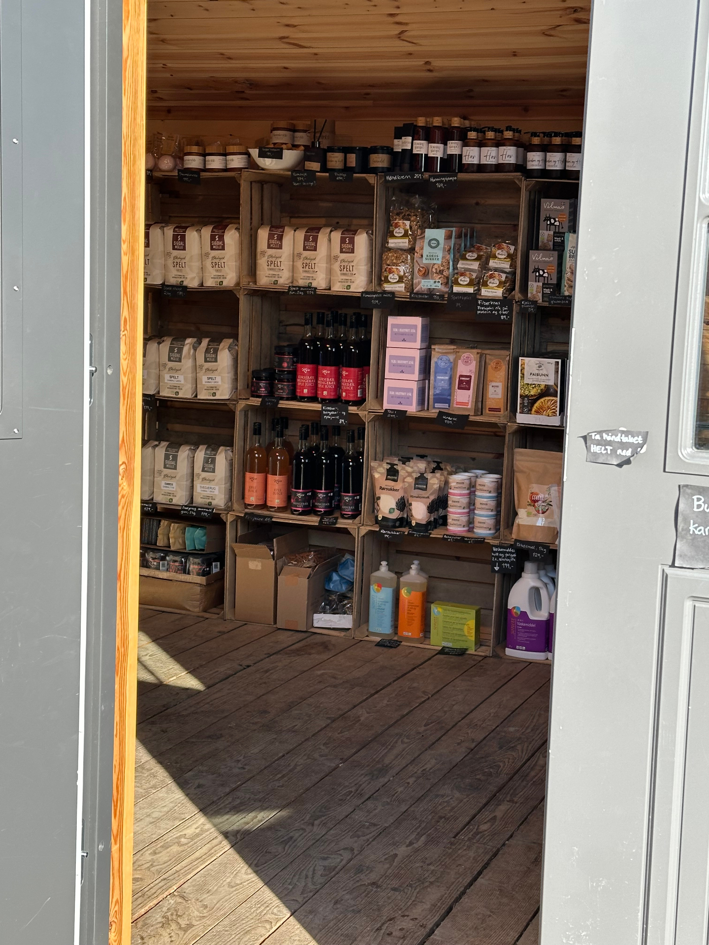 Hyller med mel, juice, krydder og tørrvarer i gårdsbutikken